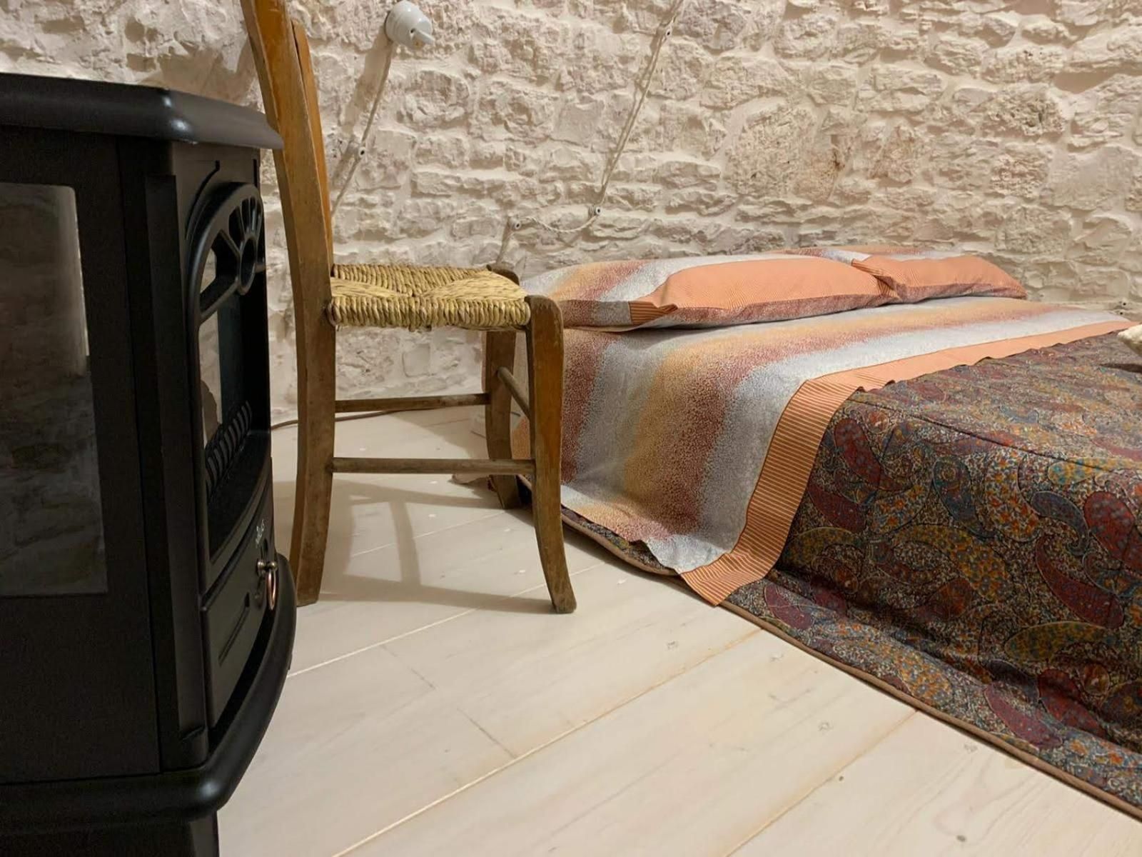 A room with a bed, a chair, and a stove.