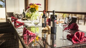 Une table à manger avec des bouteilles de vin, des verres et un vase de fleurs.