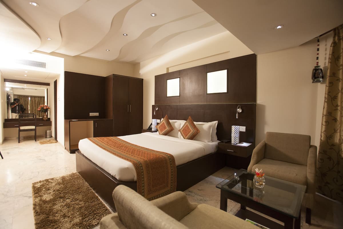 A hotel room with a large bed, a desk, a chair, and a sofa.
