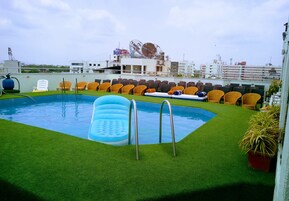 Una piscina en la azotea con césped artificial, sillones inflables y diferentes tipos de sillas.