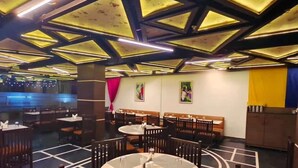 A restaurant with a modern ceiling design, multiple dining tables, and booths. - The Oasis -Vadodara  (Vadodara)