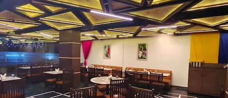 Un restaurante con un diseño moderno de techo, varias mesas para comer y cabinas.