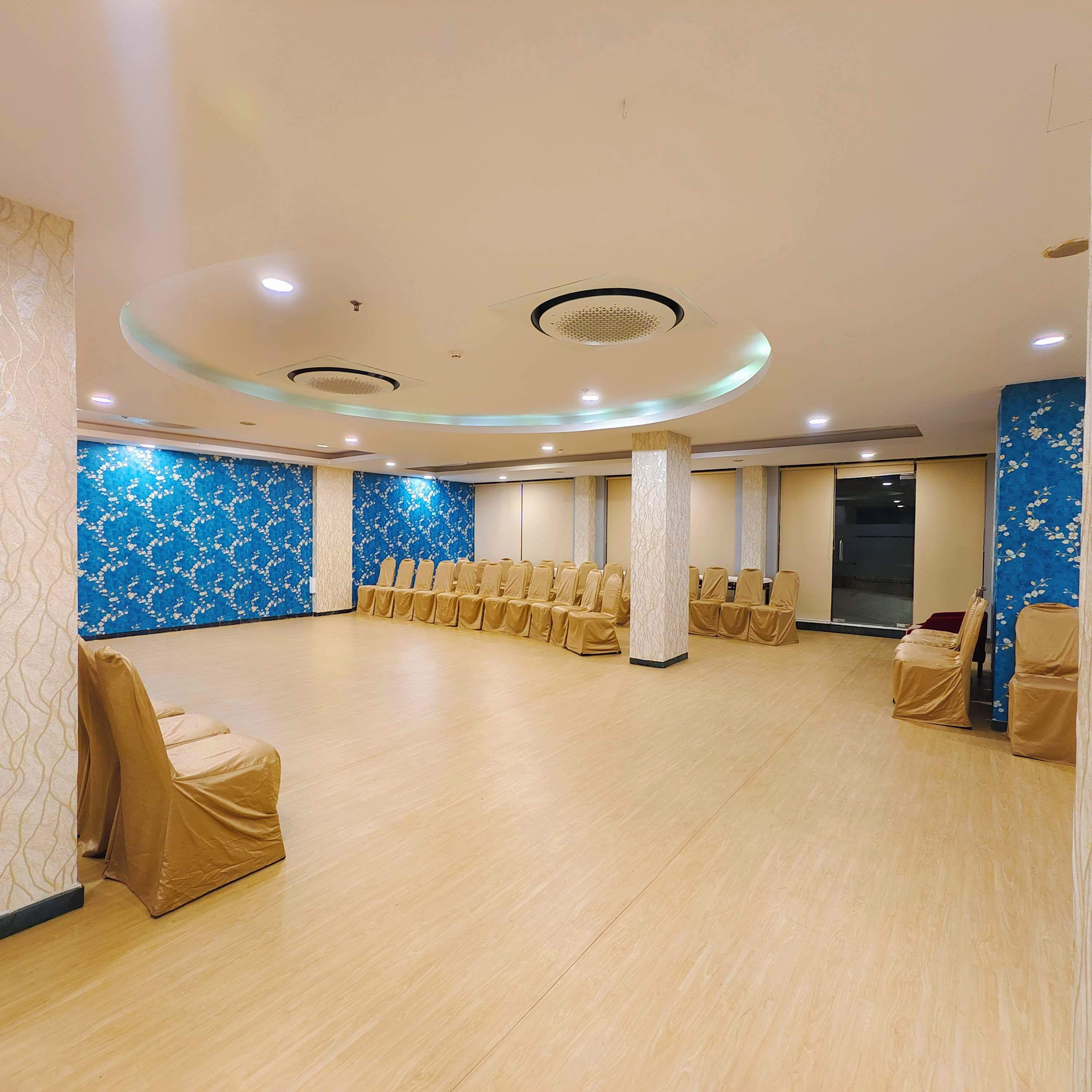 A spacious hall with rows of chairs and a high ceiling with circular lighting fixtures.