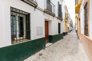 Une ruelle étroite pavée, bordée d’immeubles aux fenêtres et aux portes grillagées, ce qui laisse supposer un environnement sécurisé.