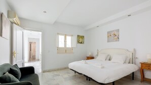 Una camera da letto con un letto, un comodino, una sedia e una porta che dà su un'altra stanza.