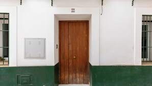 Un edificio con una porta in legno, un piccolo gradino che conduce all'ingresso e il numero '17' sopra la porta.
