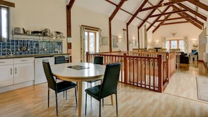 Een ruime keuken met houten balken, een eethoek met stoelen en uitzicht door een raam.