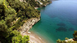 A coastal landscape with a rocky shoreline, a sandy beach, and dense greenery. - Casa Angels with shared pool (Positano)