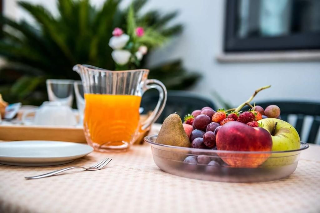 A breakfast setting with a fruit bowl, a pitcher of orange juice, and a plate on a table.