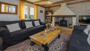A cozy living room with a fireplace, a sofa, a coffee table, and a bookshelf. - Villa Découverte, luxury house with private pool (Reilhaguet)