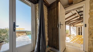 A room with a large sliding glass door leading to an outdoor area with a pool and yellow chairs. - Villa Découverte, luxury house with private pool (Reilhaguet)