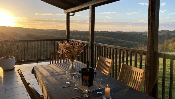 A table set for two with a view of a forested landscape and a sunset. - Villa Découverte, luxury house with private pool (Reilhaguet)