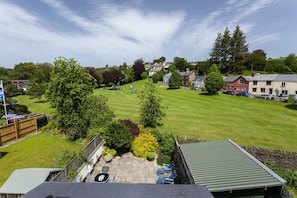 A residential area with a green lawn, a wooden fence, and a house with a green roof. - Chapel Cottage, Exford (Wheddon Cross)