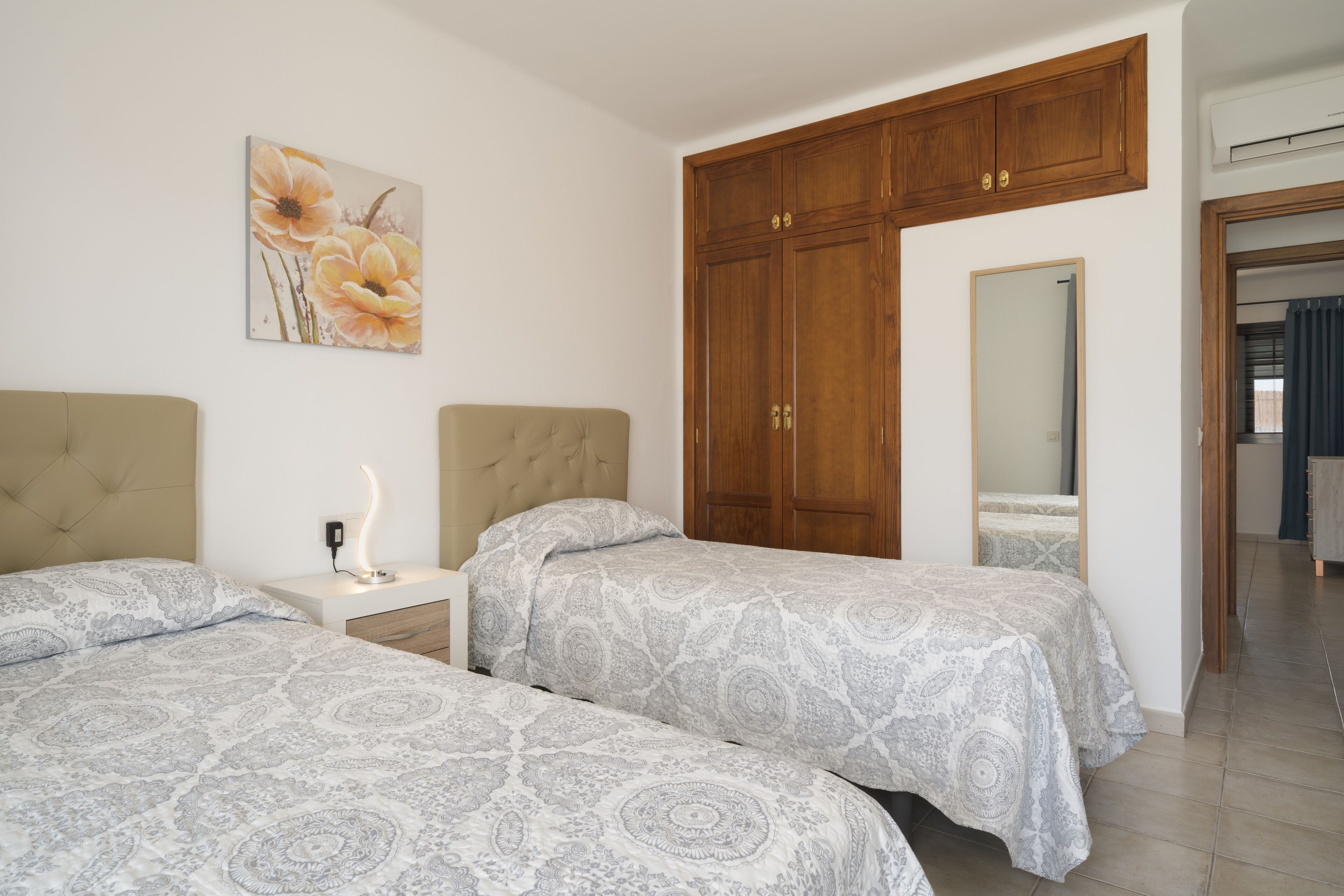 Una camera da letto con due letti, un comodino, un'armadio in legno e uno specchio.