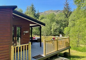 A wooden cabin with a deck, a covered seating area, and a sign reading "ASH 13". - Ash Lodge – Romantic Log Cabin, with Hot Tub, Sleeps 2 (Loch Eck)