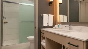 A modern bathroom with a glass shower enclosure, a white sink with a mirror, and a toilet.