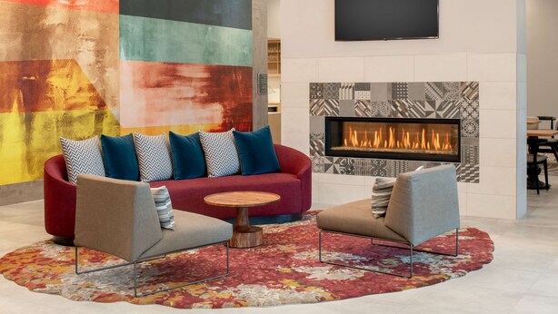 Ein modernes Wohnzimmer mit einem roten Sofa, zwei Sesseln, einem runden Holztisch und einem Kamin.