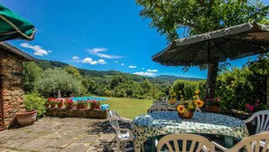 Eine Terrasse mit Tisch und Stühlen, ein Pool und Blick auf die Berge.