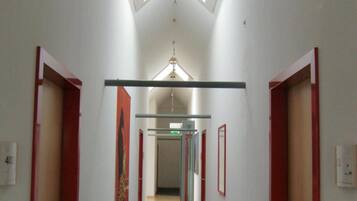 A narrow hallway with a skylight, red-framed doors, and a central corridor.