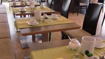 Un comedor con mesas dispuestas para un servicio de té, con teteras, tazas y platillos.