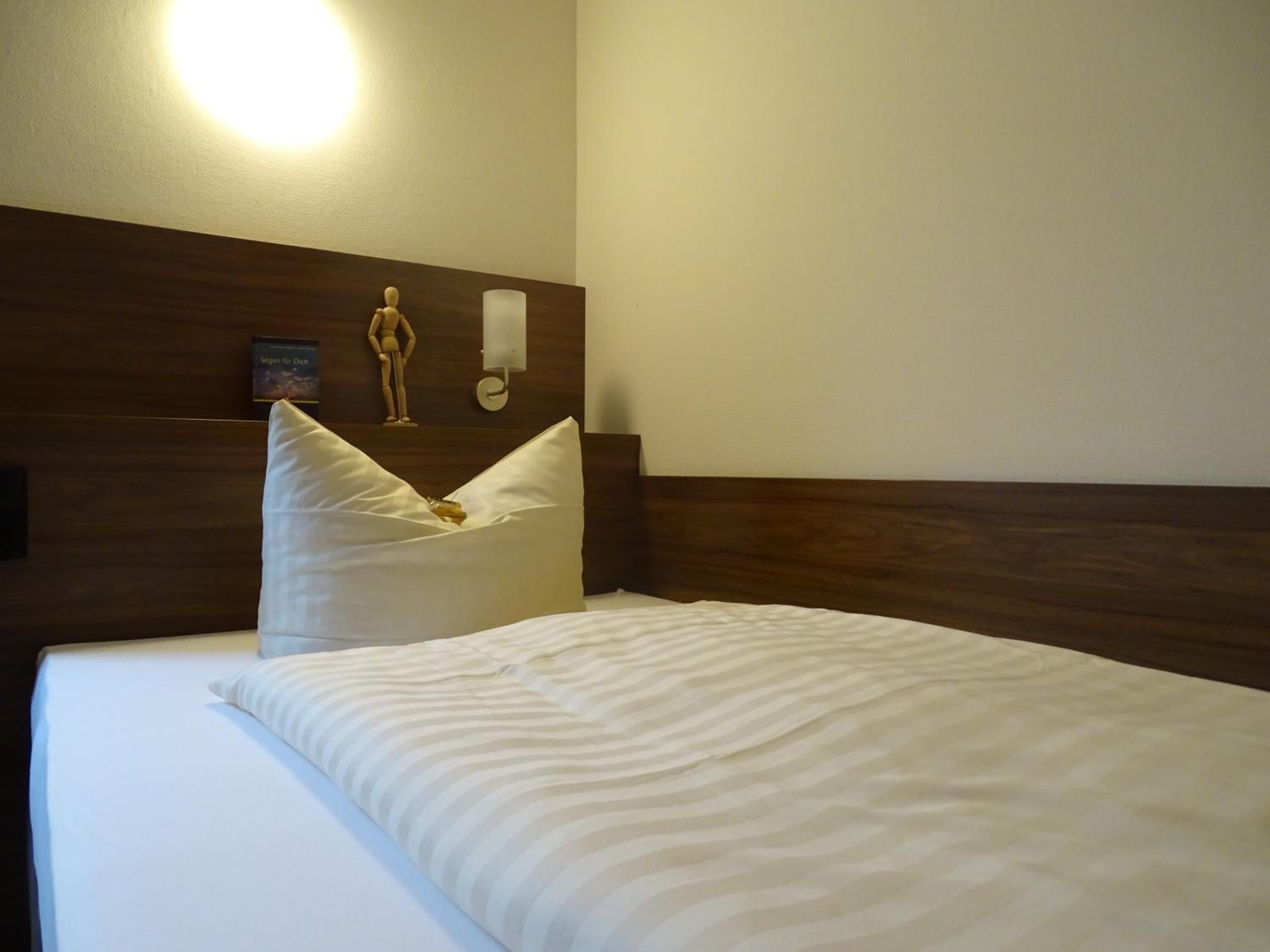 A neatly made bed with white bedding and a wooden headboard.