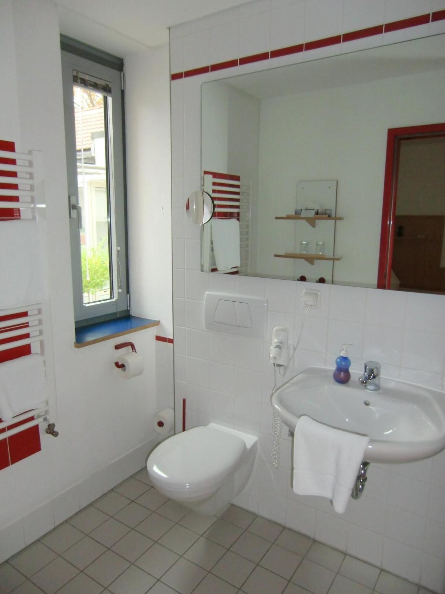 Un baño pequeño con inodoro, lavamanos y espejo.