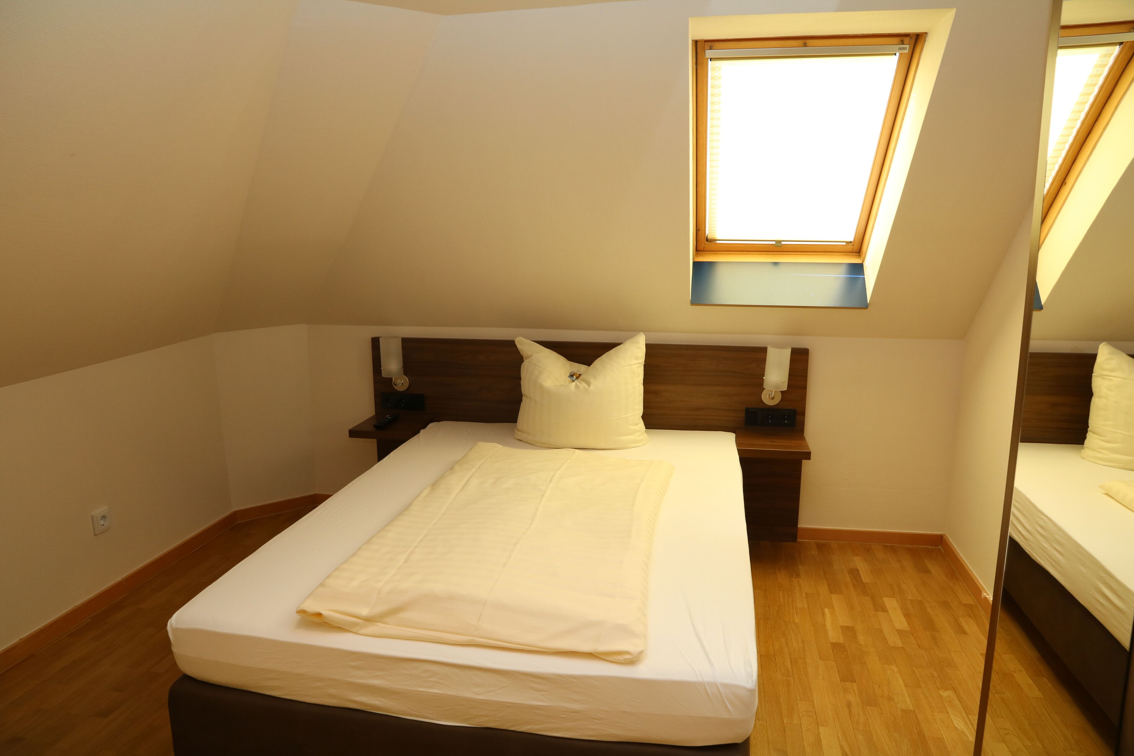 Un dormitorio con una cama individual, cabecera de madera, mesita de noche y ventana con persianas.