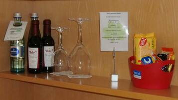 Zona de bar con botellas de licor, copas de vino y una cesta de aperitivos.