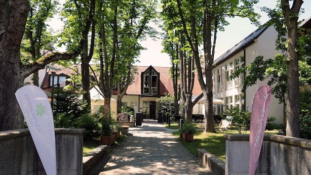A pathway leading to a building with a red-tiled roof and a large window. There are potted plants along the sides of the path. - Kolping Hotel Schweinfurt (Schweinfurt)