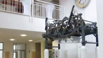 A spacious lobby with a high ceiling, a large mechanical sculpture, and a clock on the wall.