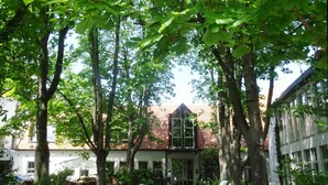 A courtyard with a building featuring a red-tiled roof and a central entrance. - Kolping Hotel Schweinfurt (Schweinfurt)