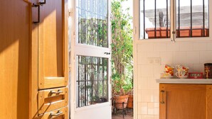 A kitchen with a white tiled backsplash, wooden cabinets, and a window with a view of a garden.