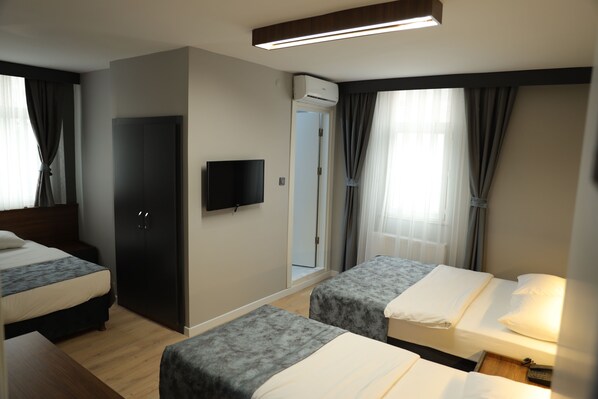 A hotel room with two beds, a TV, a wardrobe, and an air conditioning unit. - Turkuaz Hotel Gebze (Gebze)