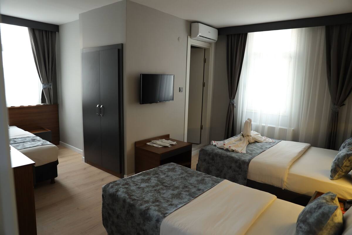 A hotel room with two beds, a TV, a wardrobe, and a small table.