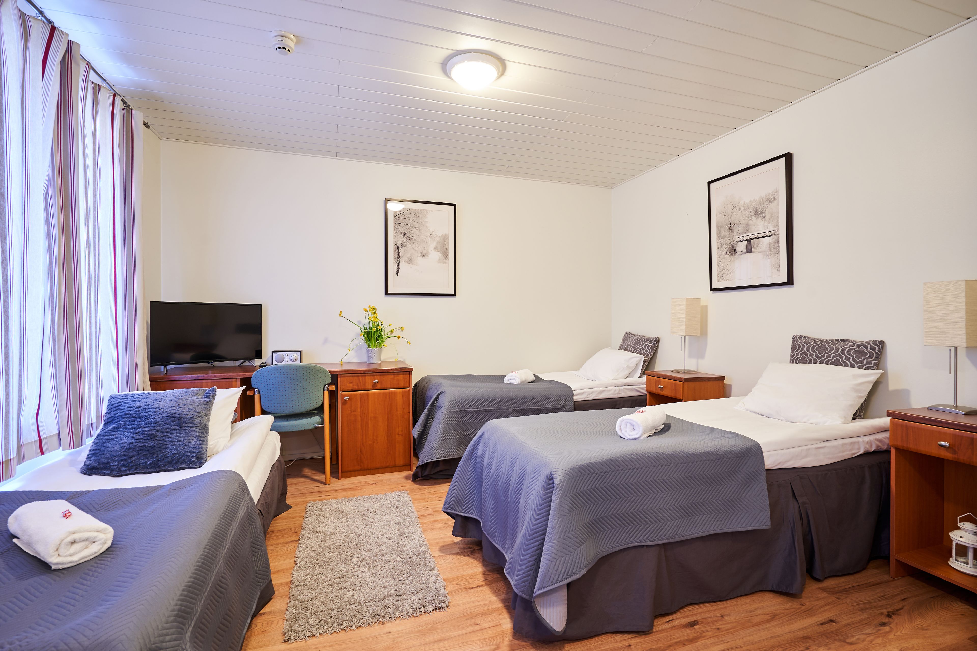 Una habitación de hotel con dos camas, televisión, escritorio y una silla.