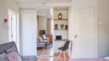 Ein modernes Schlafzimmer mit Bett, Schreibtisch und Stuhl. Es gibt eine Sitzecke mit Sofa und Couchtisch.
