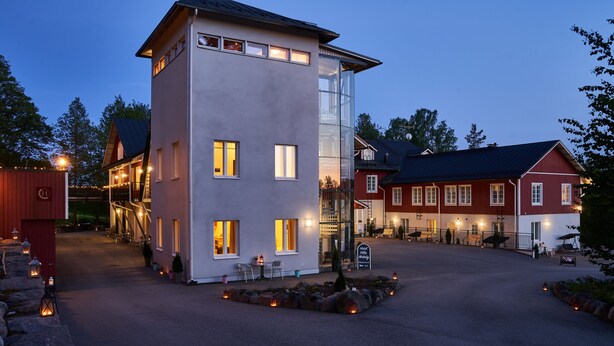 A modern building with a glass facade, a red barn-like structure, and a well-lit entrance area. - Hotel Villa Molnby (Porvoo)
