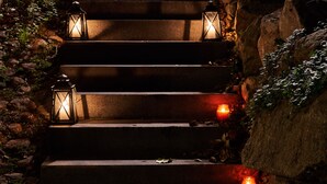 A set of stone steps with lanterns along the sides, surrounded by rocks and foliage. - Hotel Villa Molnby (Porvoo)