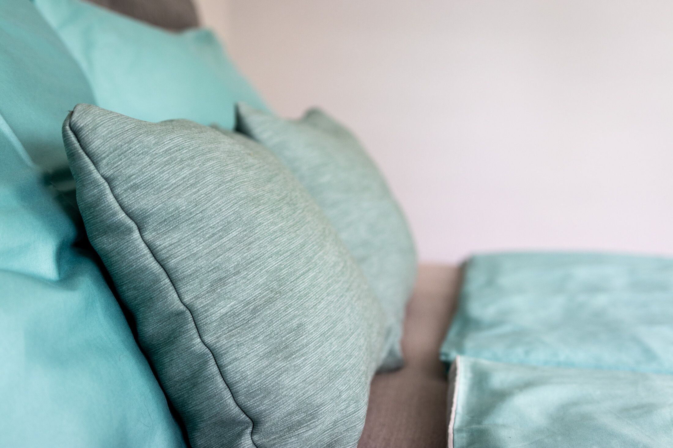 Primer plano de un almohada color aguamarina sobre una cama.
