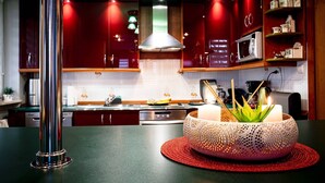 A modern kitchen with red cabinets, a stainless steel range hood, and a microwave on the countertop. - are you looking for relaxation, action and culture? (Paszkowka)