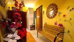 A hallway with a wooden bench, a decorative mirror, and a wall with floral designs. - Casa Arcobaleno (Rome)