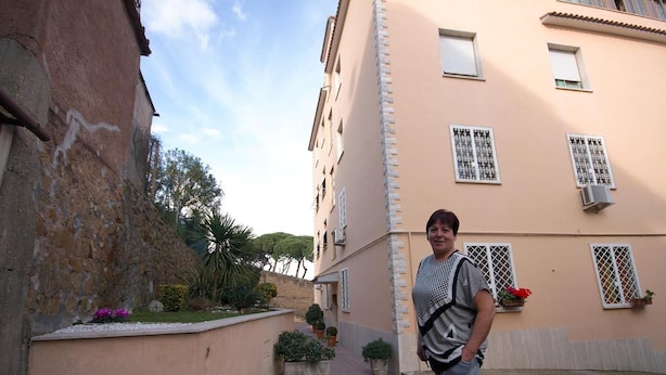 A person standing in a narrow alleyway between buildings. - Casa Arcobaleno (Rome)