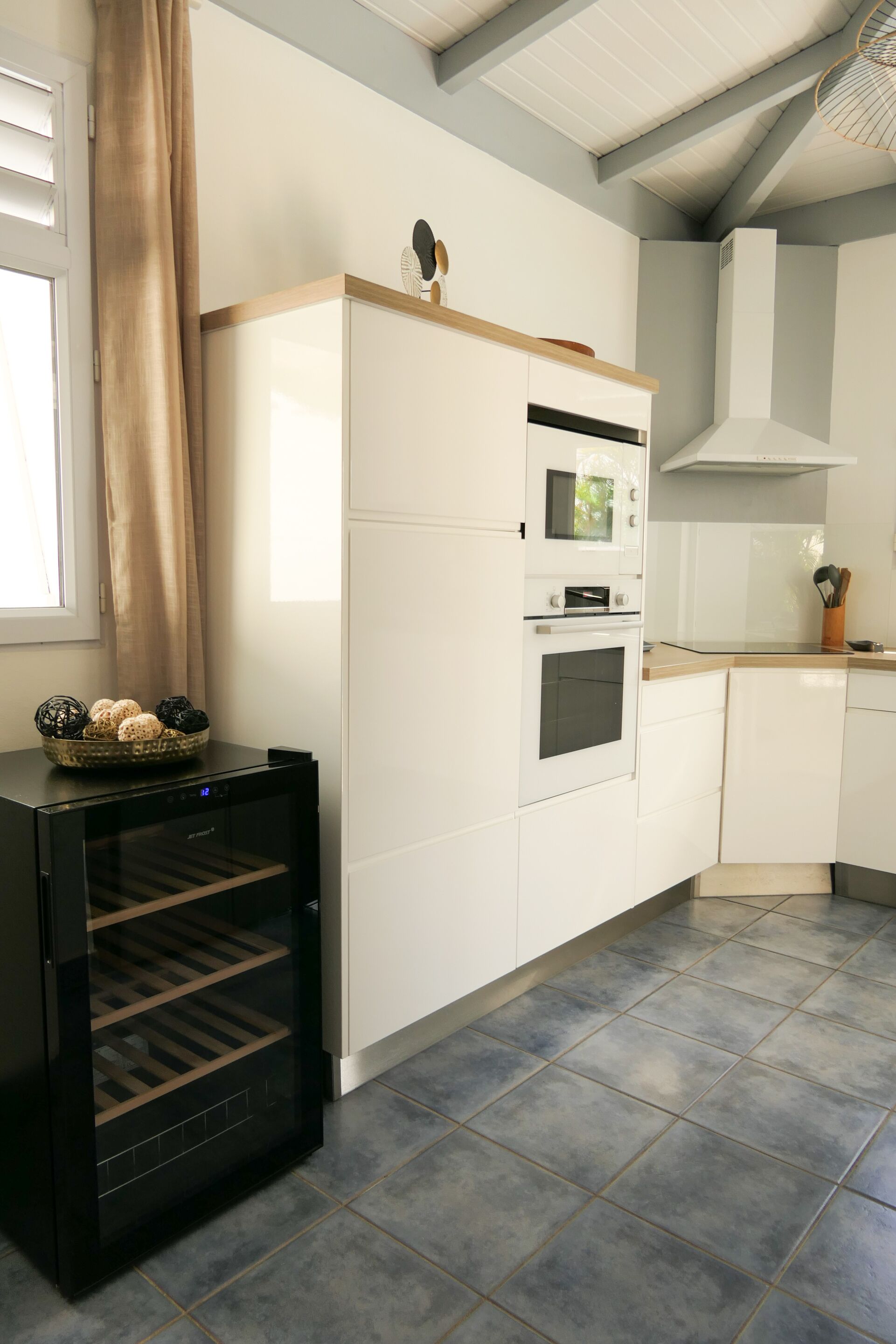 Een keuken met witte kasten, een inbouwoven en een zwart apparaat met een glazen deur.