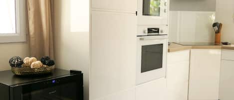 Uma cozinha com armários brancos, forno embutido e eletrodoméstico preto com porta de vidro.