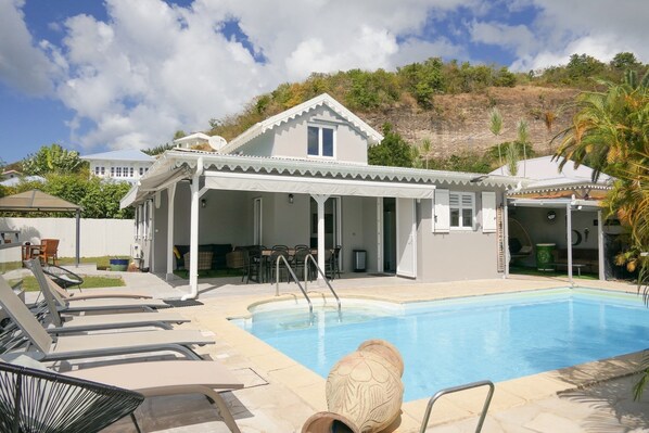 A poolside area with lounge chairs, a covered seating area, and a pool.