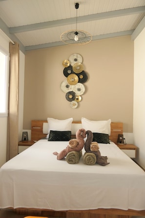 A neatly made bed with a white sheet, two pillows, and a decorative wall piece above it.