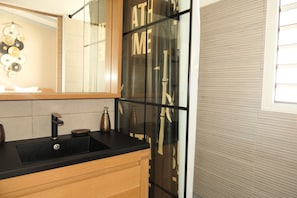 A modern bathroom with a black sink, wooden cabinets, and a large mirror.