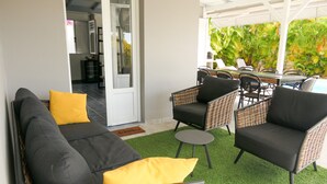 A covered outdoor seating area with wicker furniture, a sofa, and a dining table. - Magnificent villa close to the sea (Le Diamant)