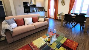 A modern living room with a sofa, a coffee table, and a dining area with chairs and a table. - Rigoletto Massena hyper center, 5 min beaches (Nice)