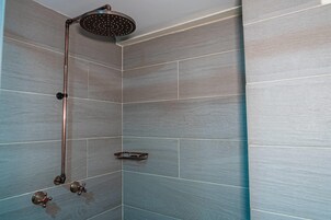 Una ducha con cabezal de ducha de lluvia, un cabezal de ducha manual y un grifo de mano.